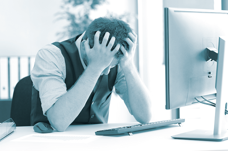 Deprimeret forretningsmand efter konkurs beklagende med hænderne på hovedet i en stationær på kontoret